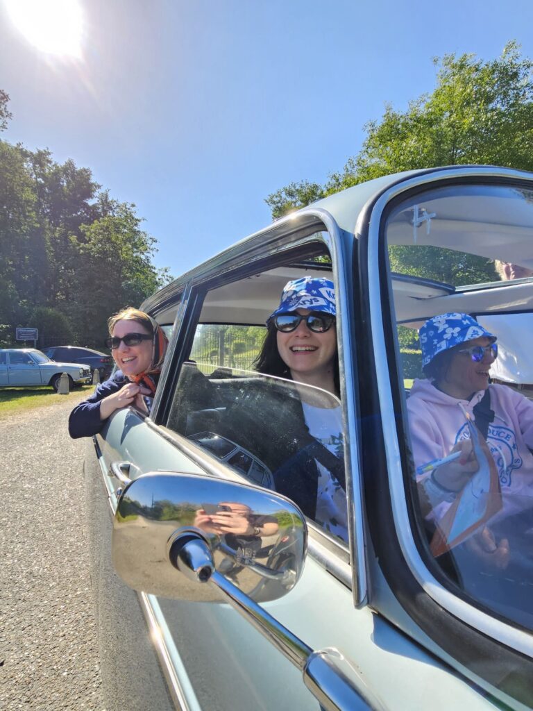 Personnes souriantes dans une voiture classique ensoleillée.